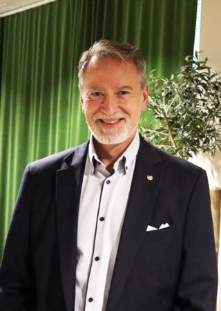 Man i skjorta och kavaj med grön bakgrund